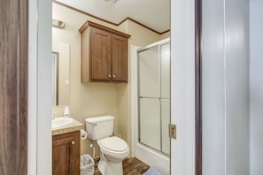 Een badkamer met toilet, wastafel, kast en een douchedeur.