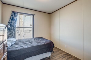 A bedroom with a bed, a window with blinds, a wooden dresser, and a wardrobe.