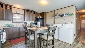 Une cuisine compacte avec des meubles en bois, une table à manger avec des chaises, un réfrigérateur et un lave-linge.