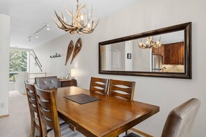 A dining room with a large wooden table, six chairs, a chandelier, and a large mirror on the wall. - Central Condo W/ Resort Amenities I Pool + Hot Tub (Vail)