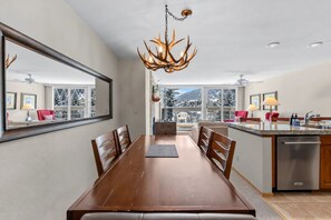 Una cocina moderna con comedor, ventanas amplias y una lámpara de araña con forma de cuerno de ciervo.