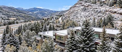 A resort with modern buildings surrounded by snow-covered trees and mountains.