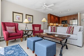 A living room with a sofa, two armchairs, a coffee table, and a kitchen in the background. - Central Condo W/ Resort Amenities I Pool + Hot Tub (Vail)