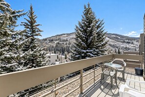 A balcony with a view of snow-covered trees and a distant mountain range. - Central Condo W/ Resort Amenities I Pool + Hot Tub (Vail)