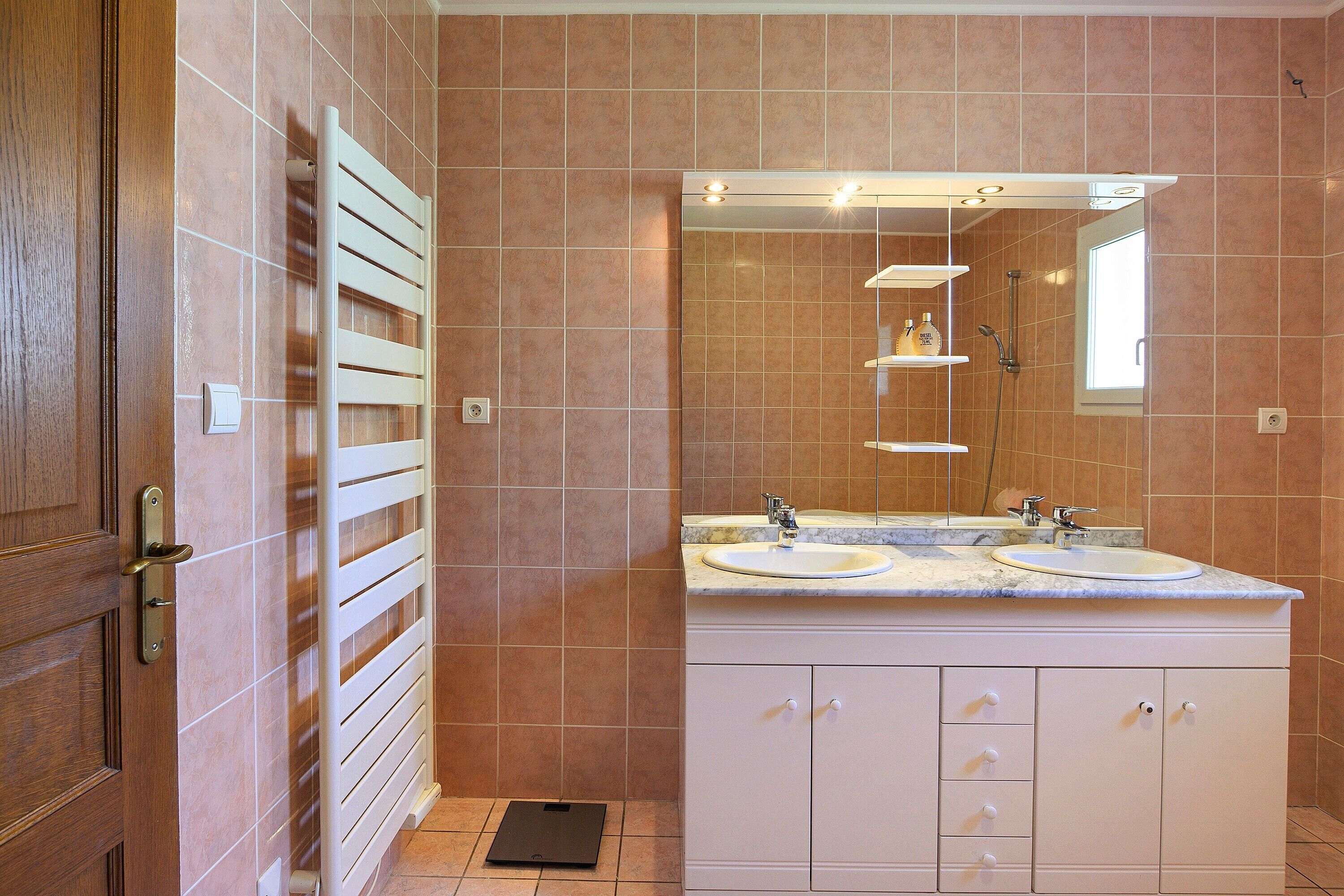 A bathroom with a double sink, a mirror, and a towel rack.