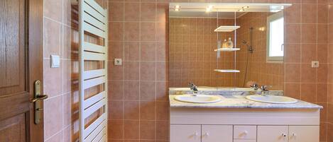 A bathroom with a double sink, a mirror, and a towel rack.