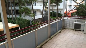 Ein Balkon mit gefliestem Boden, Metallgeländer und einer Klimaanlage.
