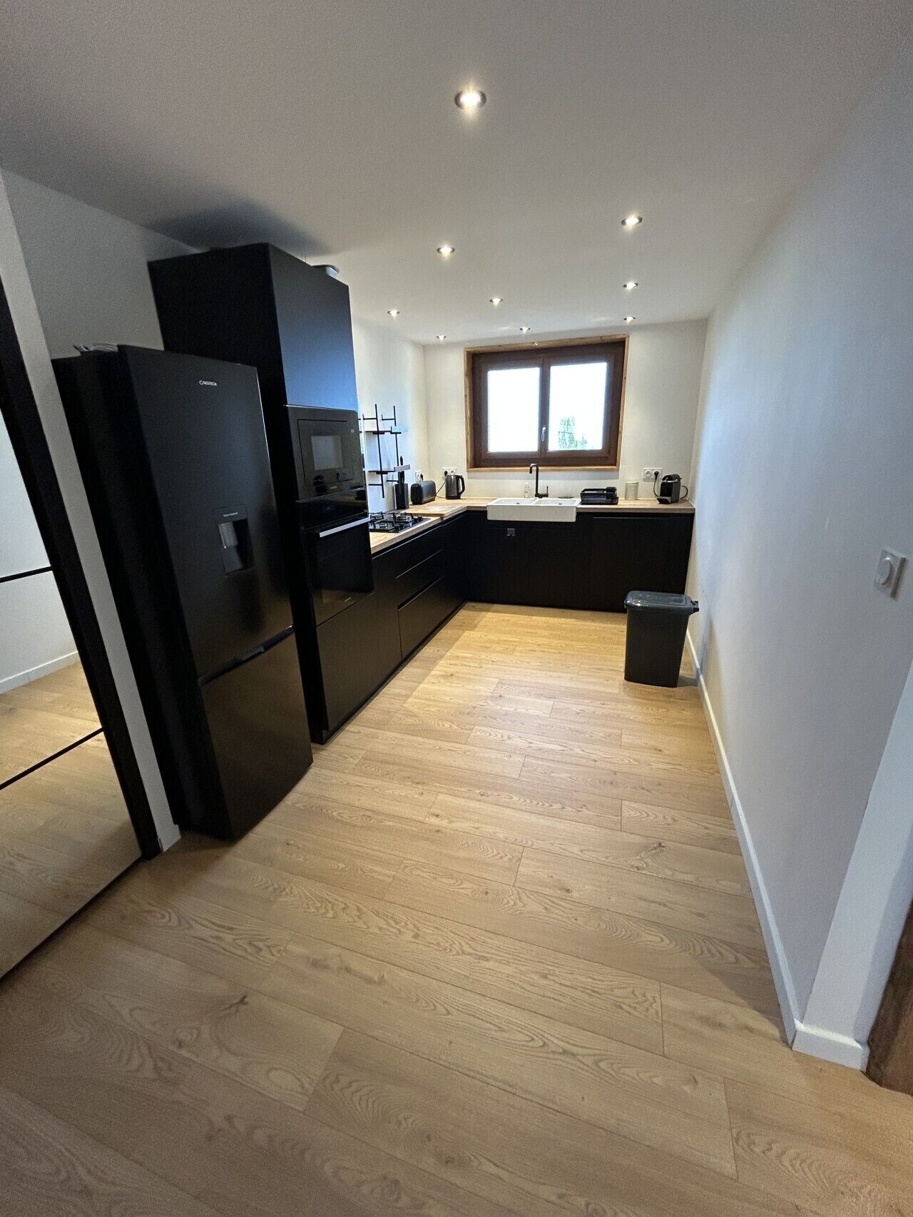 A modern kitchen with a built-in oven, microwave, and a window above the sink.