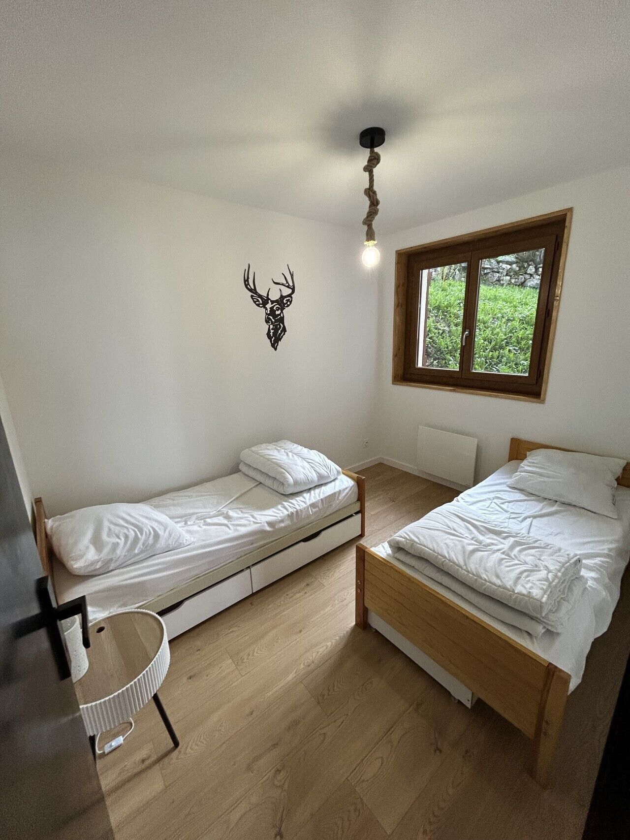 Alojamento pequeno e com um quarto, equipado com duas camas individuais, uma decoração de cabeça de veado na parede, janela com vista para o verde e design moderno e simples.