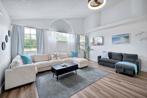 Ein modernes Wohnzimmer mit einem Ecksofa, einem Couchtisch und einem grauen Teppich.