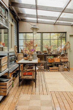 Ein rustikaler Raum mit Holzboden, einem großen Fenster und verschiedenen Aufbewahrungsbehältern.