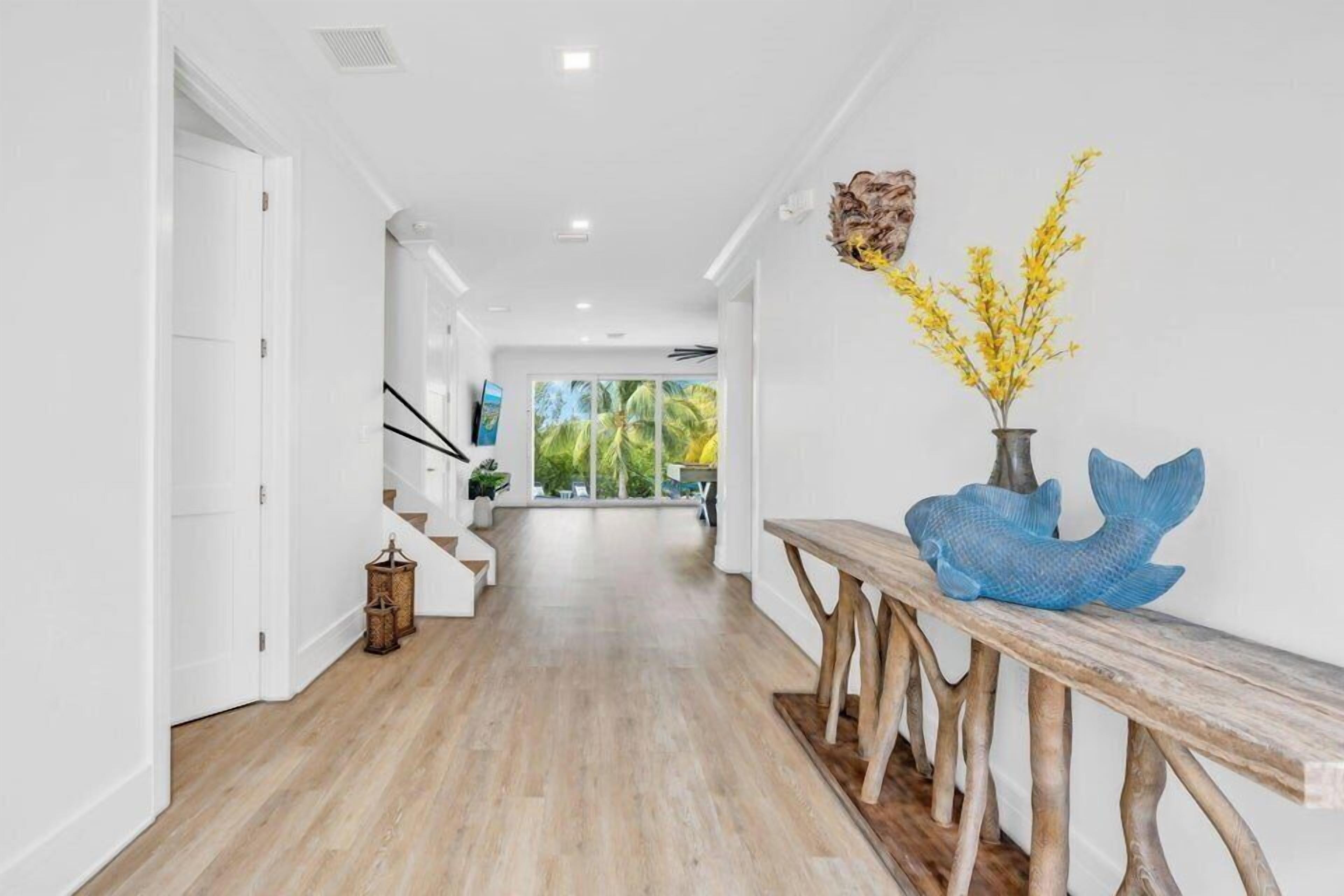 A modern hallway with wooden flooring, white walls, and a bench with decorative items.