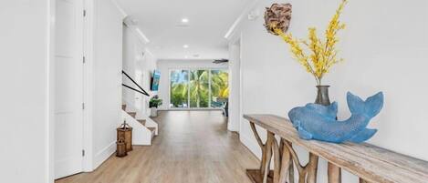 A modern hallway with wooden flooring, white walls, and a bench with decorative items.