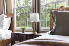 A neatly made bed with white linens, a bedside table with a lamp, and a view of trees through a window with curtains. - Horse Country Escape 15 Minutes to WEC & Adventure Springs (Ocala)