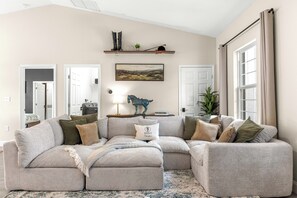 A living room with a sectional sofa, a fireplace, a mounted painting, and a window with curtains. - Horse Country Escape 15 Minutes to WEC & Adventure Springs (Lutz)