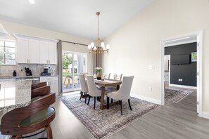 A modern kitchen with white cabinets, a granite countertop, and a dining area with a wooden table and chairs. - Horse Country Escape 15 Minutes to WEC & Adventure Springs (Ocala)