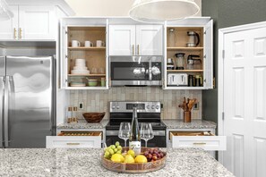 A modern kitchen with white cabinets, a stainless steel refrigerator, an oven, a microwave, and a coffee maker. - Horse Country Escape 15 Minutes to WEC & Adventure Springs (Ocala)