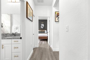 A hallway leading to a bedroom with a bed, a bathroom with a sink, and a framed picture on the wall. - Horse Country Escape 15 Minutes to WEC & Adventure Springs (Lutz)