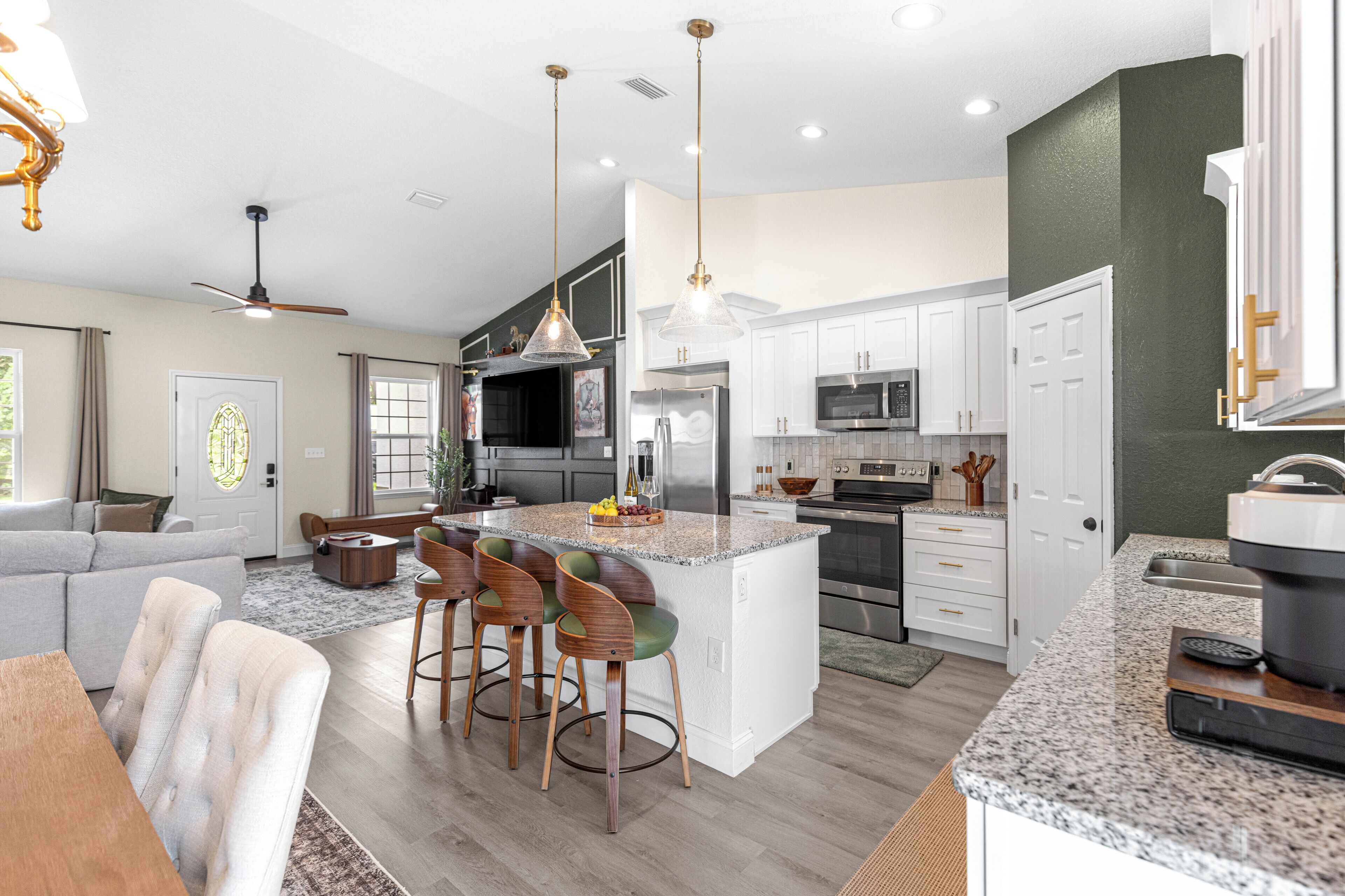 A modern kitchen with a central island, bar stools, and stainless steel appliances.