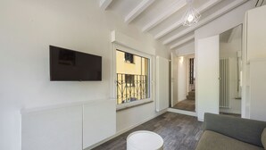 A hallway with a TV mounted on the wall, a radiator, a window with a metal gate, and a sofa. - Vettori Hideaway by MMega (Florence)
