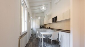 A narrow kitchen with a dining area, white cabinetry, and pendant lighting. - Vettori Hideaway by MMega (Florence)