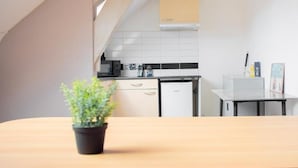 Et køkken med hvide skabe, et lille køleskab og et flisebeklædt backsplash.