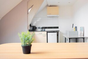 Et køkken med hvide skabe, et lille køleskab og et flisebeklædt backsplash.