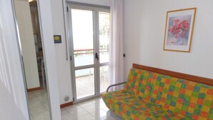 A room with a sofa, a sliding glass door, a framed picture on the wall, and a tiled floor. - Space and Comfort for Everyone Near the Beach (San Michele al Tagliamento)