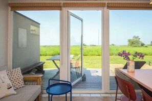 Ein Zimmer mit einer Schiebetür zum Außenbereich, einem Sofa, einem Fernseher und einem Tisch mit Stühlen.