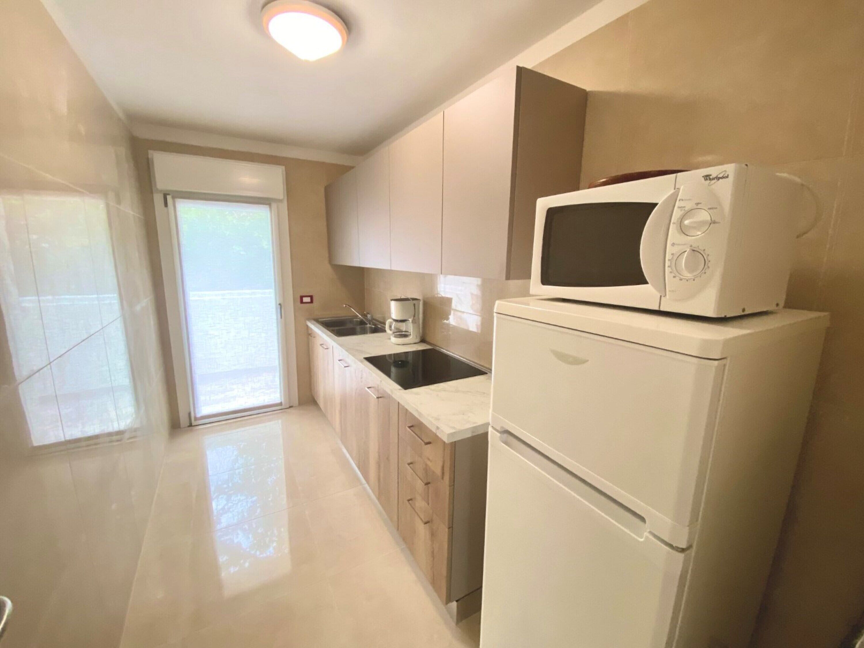A modern kitchen with a microwave, coffee maker, and a refrigerator.