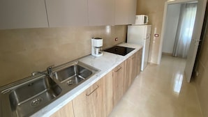 A modern kitchen with two sinks, a coffee maker, and a refrigerator. - Modern Stay in a Central Area in Bibione (San Michele al Tagliamento)