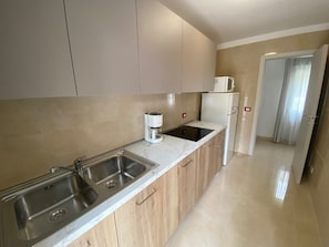 A modern kitchen with two sinks, a coffee maker, and a refrigerator. - Modern Stay in a Central Area in Bibione (San Michele al Tagliamento)
