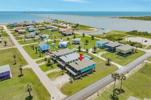 An aerial view of a coastal residential area with houses, roads, and a body of water.