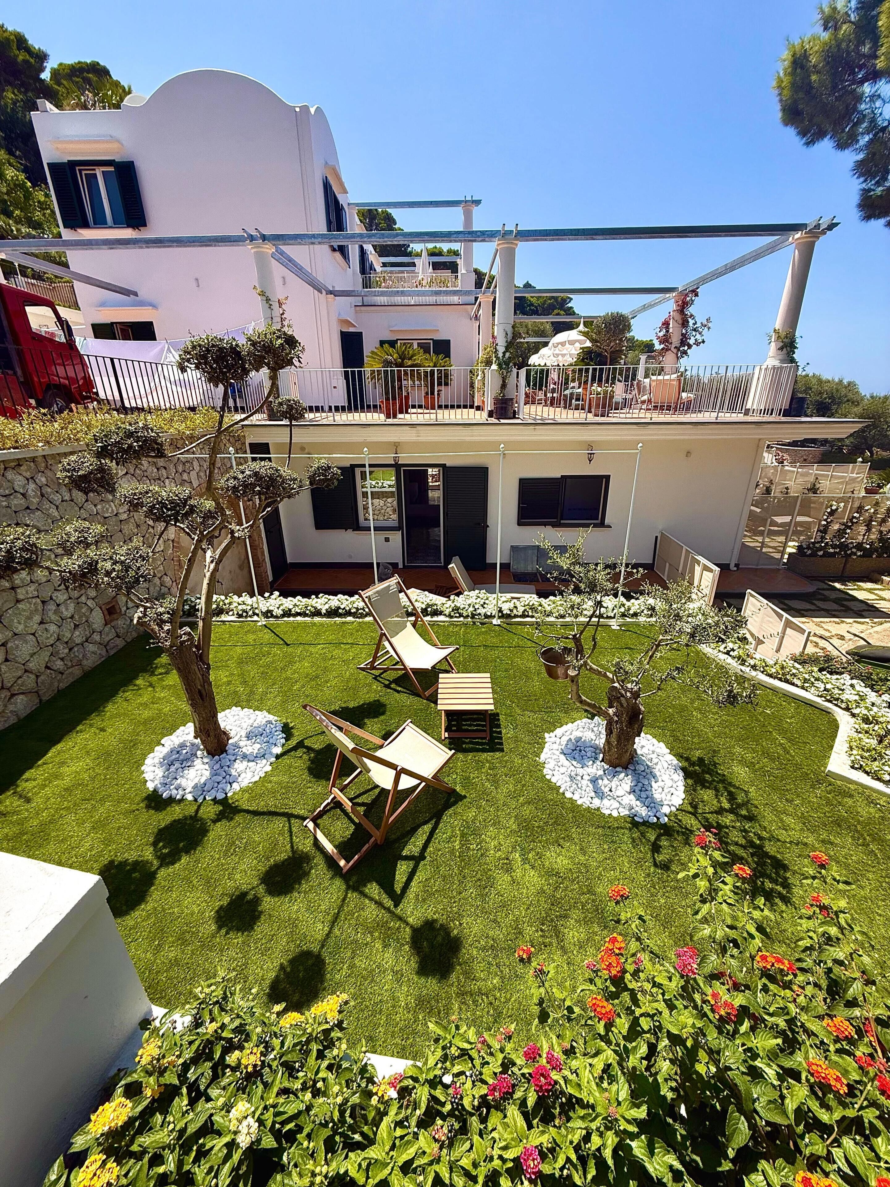 Una casa moderna con balcón, mobiliario exterior y un jardín lleno de flores.
