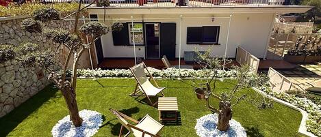 Una casa moderna con balcón, mobiliario exterior y un jardín lleno de flores.