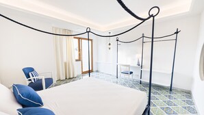 A hotel room with a bed, a chair, a desk, and a window.