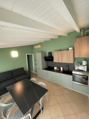 Una cocina compacta con comedor, horno empotrado, microondas y pileta.
