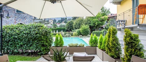 An outdoor patio with a table and chairs, a pool, and a view of the surrounding area.
