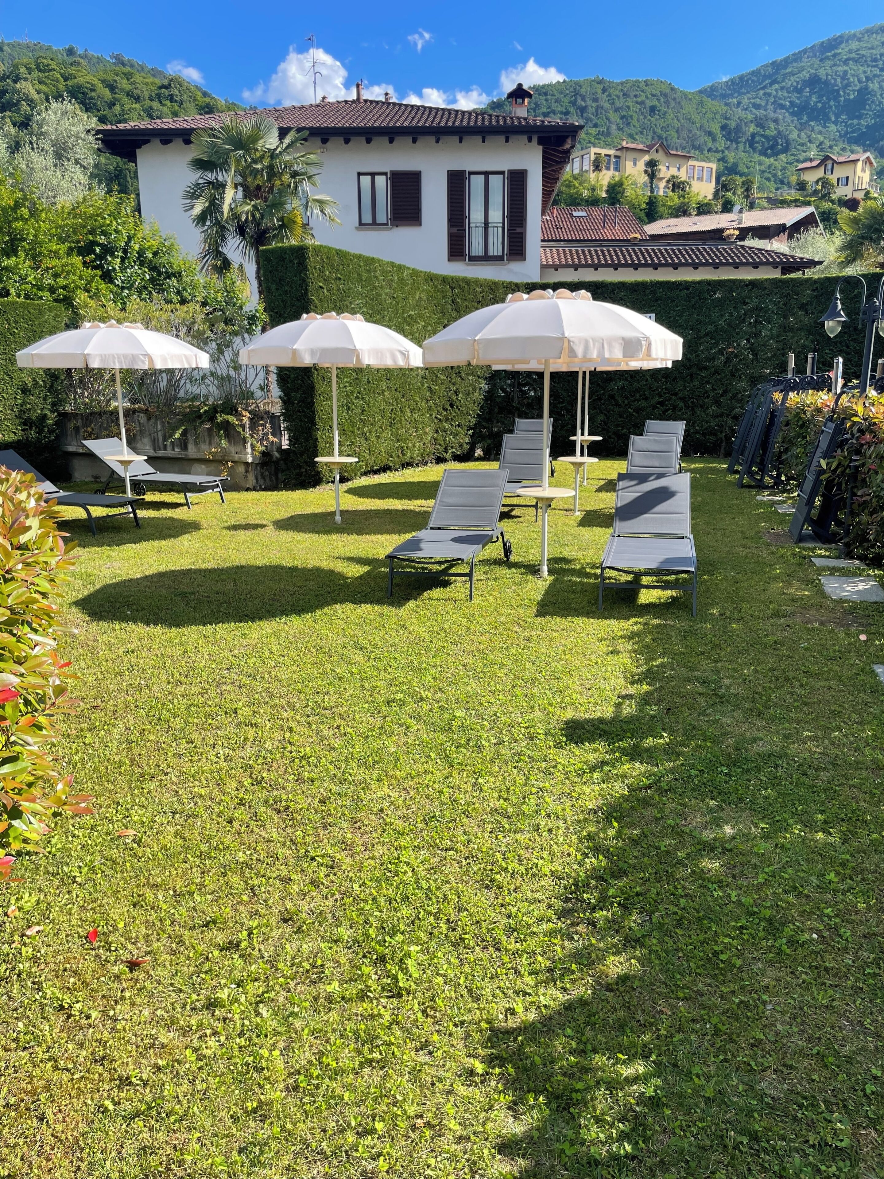 A well-maintained outdoor area with lounge chairs and umbrellas, surrounded by lush greenery and a mountain backdrop.