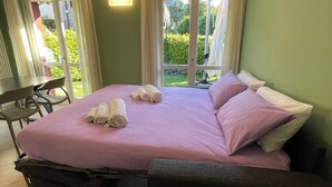 A room with a bed, a chair, a table, and a potted plant. - Bellagio Lake Home (Bellagio)