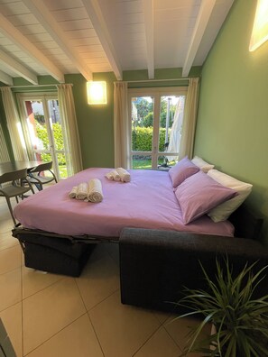 Una habitación con cama, una silla, una mesa y una planta en maceta.