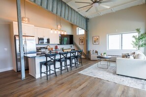 A modern kitchen with bar stools, a dining table, and a large window. - Airplane/Hanger Apartment 2 bedrooms 2 bathrooms #3 (Salado)