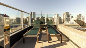 Eine Dachterrasse mit Liegestühlen und Pool, mit Blick auf die Stadt.