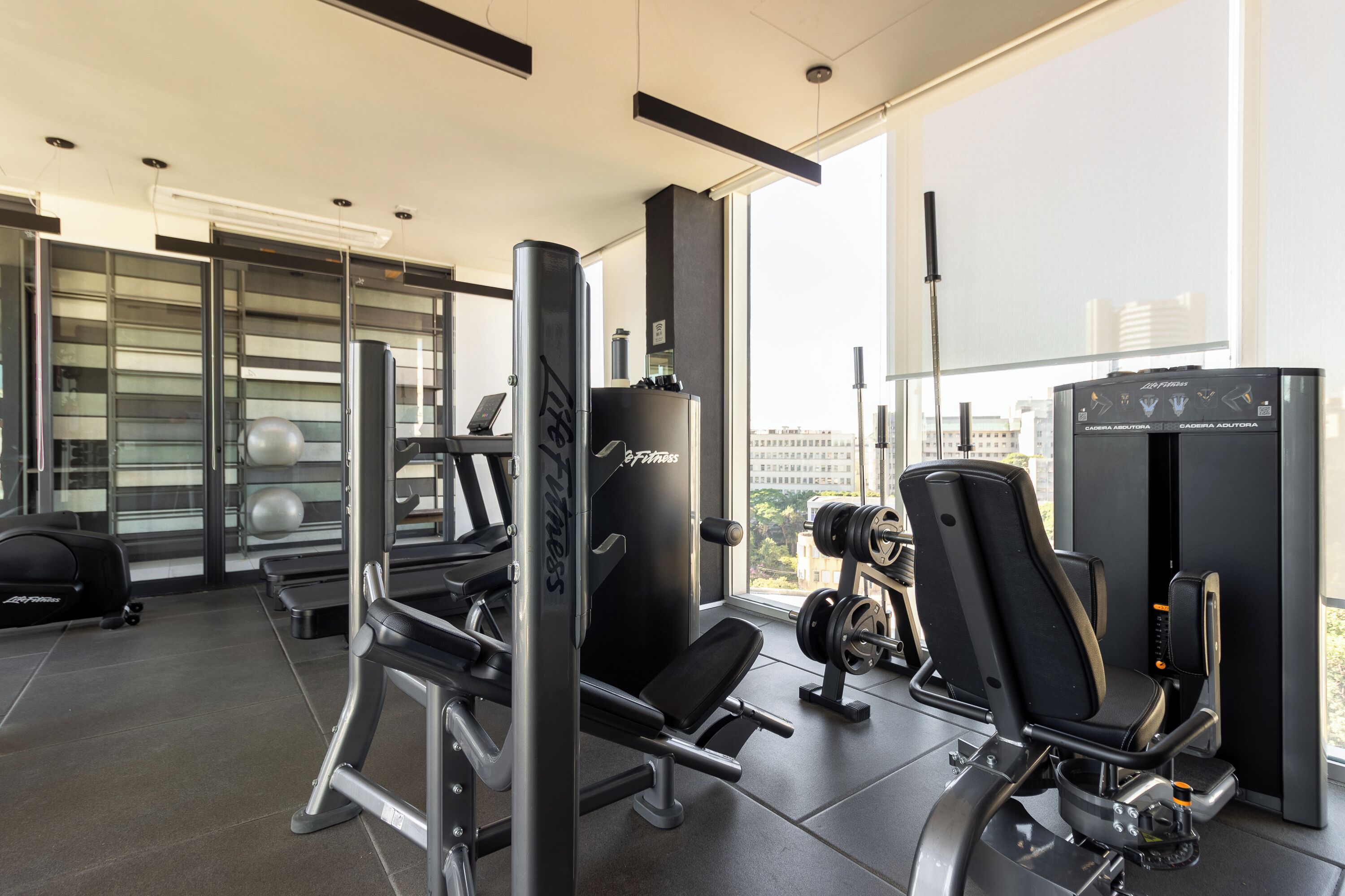 A modern gym with weightlifting equipment, a bench press, and a treadmill.