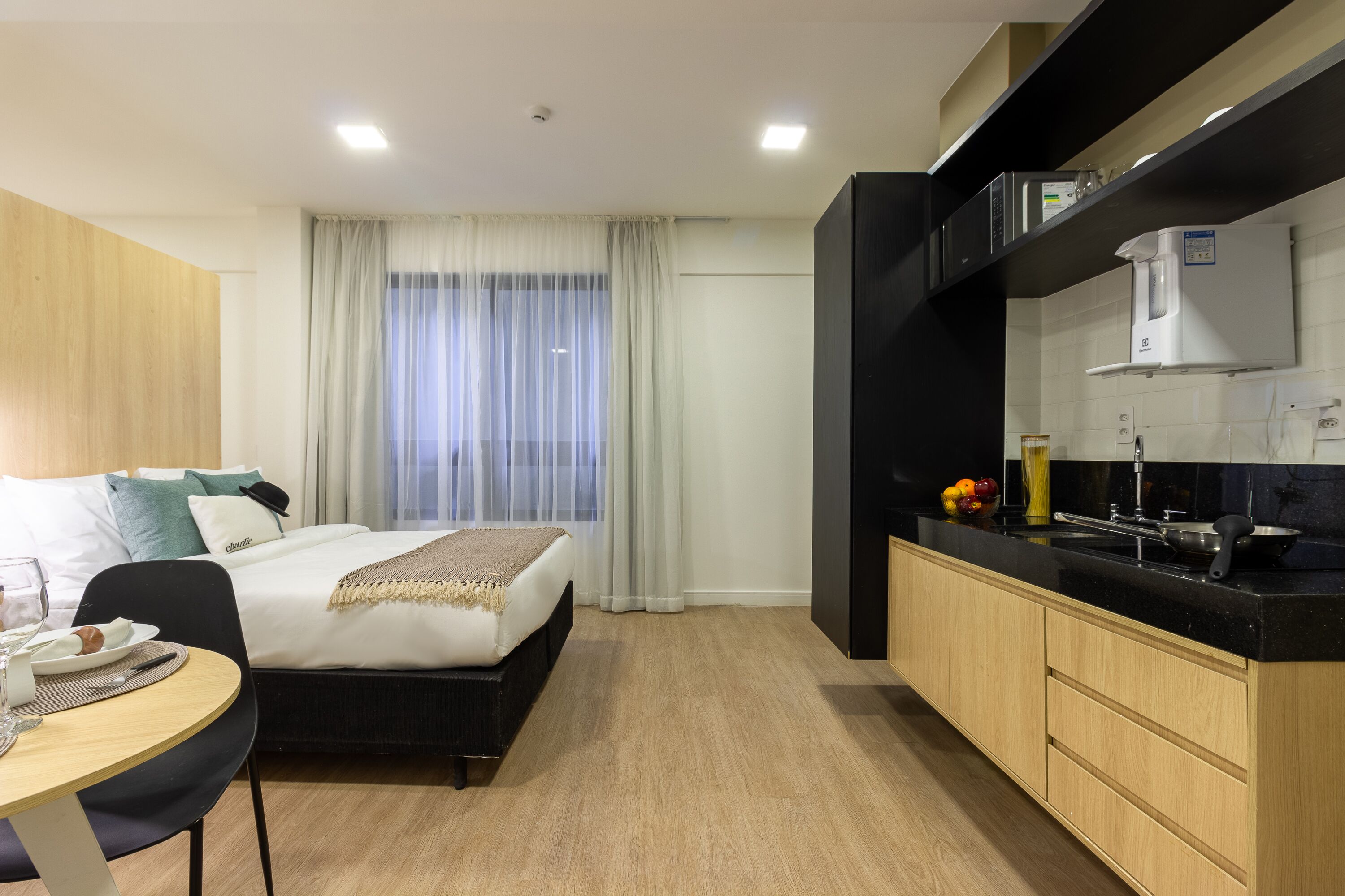 Ein Hotelzimmer mit Bett, Nachttisch und einer Küchenzeile.