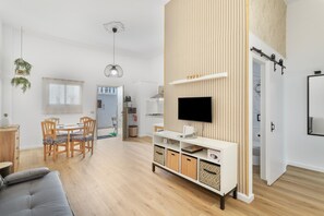 Ein modernes Wohnzimmer mit Essbereich, Holzboden, einem Flachbildfernseher und eingebauten Stauraum.
