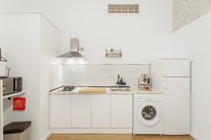 Eine kompakte Küche mit Mikrowelle, Herd, Spüle und Waschmaschine.