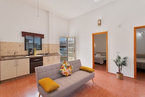 A modern kitchen with a grey sofa, yellow cushions, and a potted plant. - Vacation Home 'Jomeca 2' with Mountain View, Shared Pool and Wi-Fi (San Bartolomé de Tirajana)