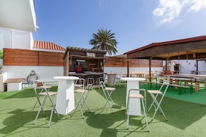 An outdoor patio area with a bar, seating, and a palm tree. - Vacation Home 'Jomeca 2' with Mountain View, Shared Pool and Wi-Fi (San Bartolomé de Tirajana)
