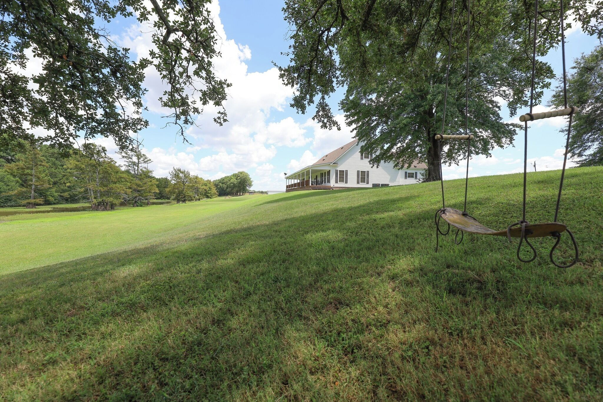 A house with a porch, surrounded by a grassy field and trees.
